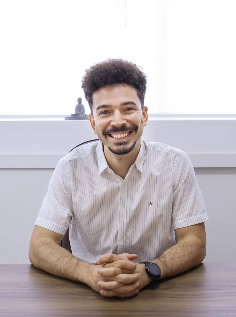 Dr. Lúcio Moreira sorrindo, sentado à mesa.